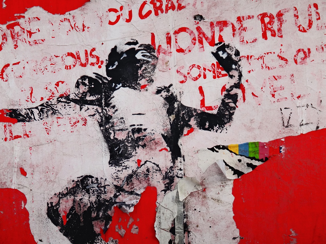 Grafitti art against a white wall. Words painted in red run diagonally across the wall, but too many letters have been washed off to make them out. In the center, the countours and shadows of a human figure are painted in black. It's head is facing up and to the right of the image, it's left arm extends out of frame, and it's right arm appears to be holding a bottle. Like the words, the paint of the figure has been too washed off to make out finer details